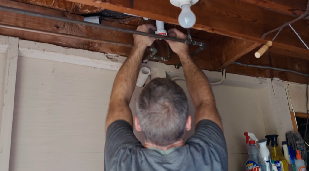 Plumber repairing drain pipes in an exposed ceiling