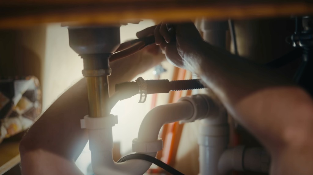 Plumber repairing under-sink plumbing